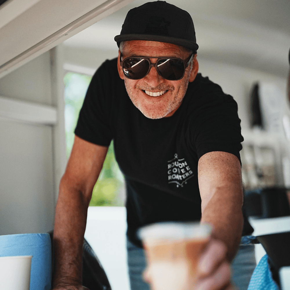 Coffee roaster serving a cup of coffee while wearing sunglasses