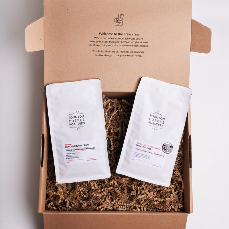 Two coffee bags in a cardboard box with branding and text.