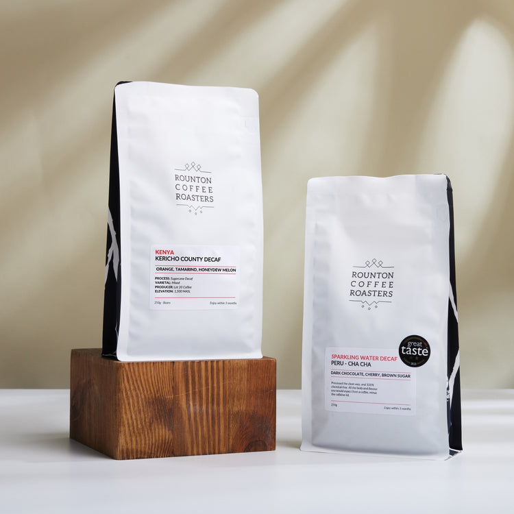 Two coffee bags from Rounton Coffee Roasters on a wooden block with a neutral background