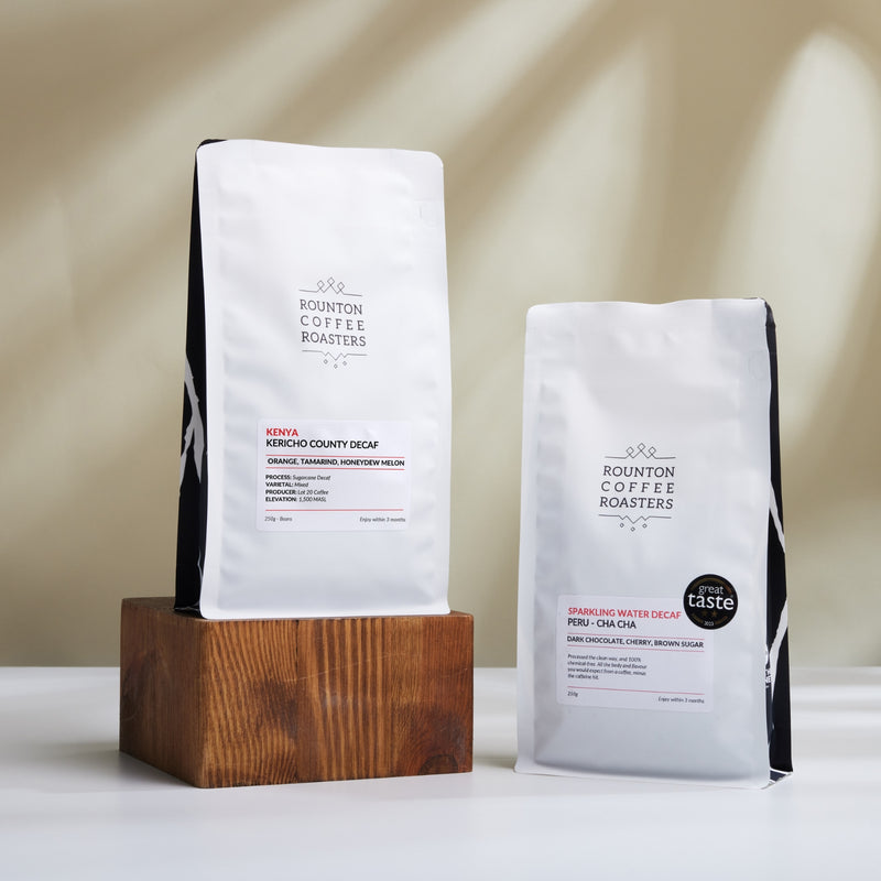 Two coffee bags from Rounton Coffee Roasters on a wooden block with a neutral background