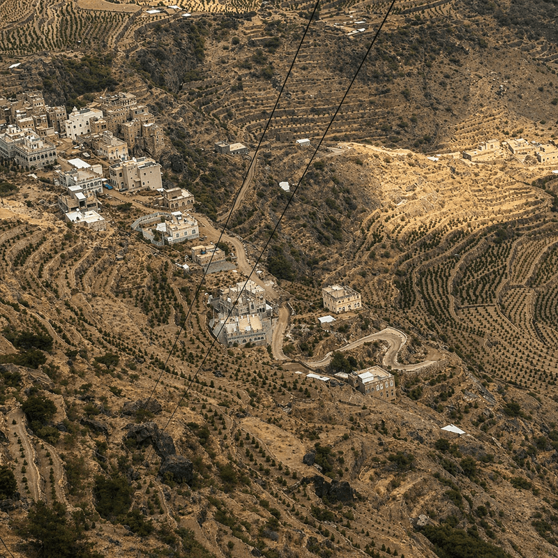 Aerial view of a mountain village with winding roads and terraced fields.